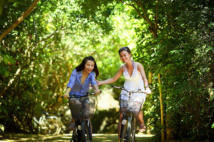 two, girl, riding, bicycle, passing, green, tunnel, trees, biking, bike