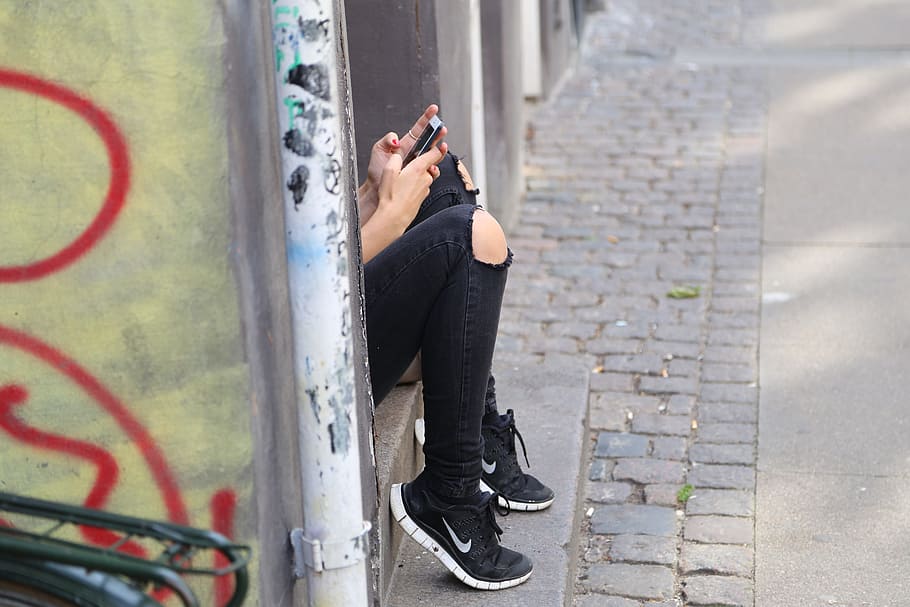 shallow, focus photography, person, wearing, distressed, black, jeans, using, smartphone, girl