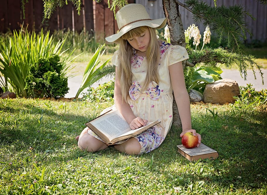 girl, wearing, dress, sitting, grass, holding, apple, reading book, child, read