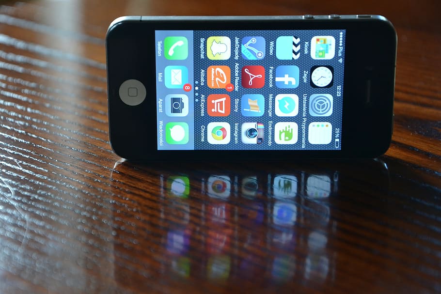 turned-on iphone 4, 4s, displaying, home screen, wood surface, iphone, iphone 4, phone, black, cell