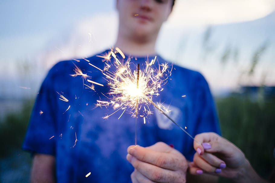 person holding firecracker, adult, blur, boy, celebration, child, festival, fun, girl, grass