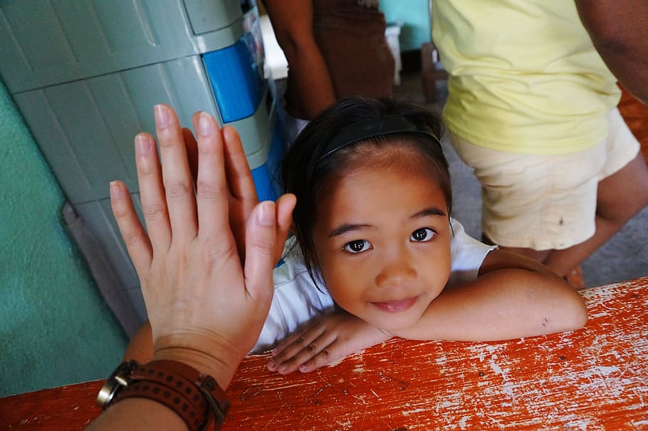 sonriente, niña, inclinada, al lado, rojo, de madera, mesa, Filipinas, Voluntario, Voluntariado