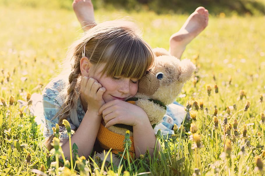 girl, brown, bear, push, toy, smiling, white, lying, grass field, teddy bear