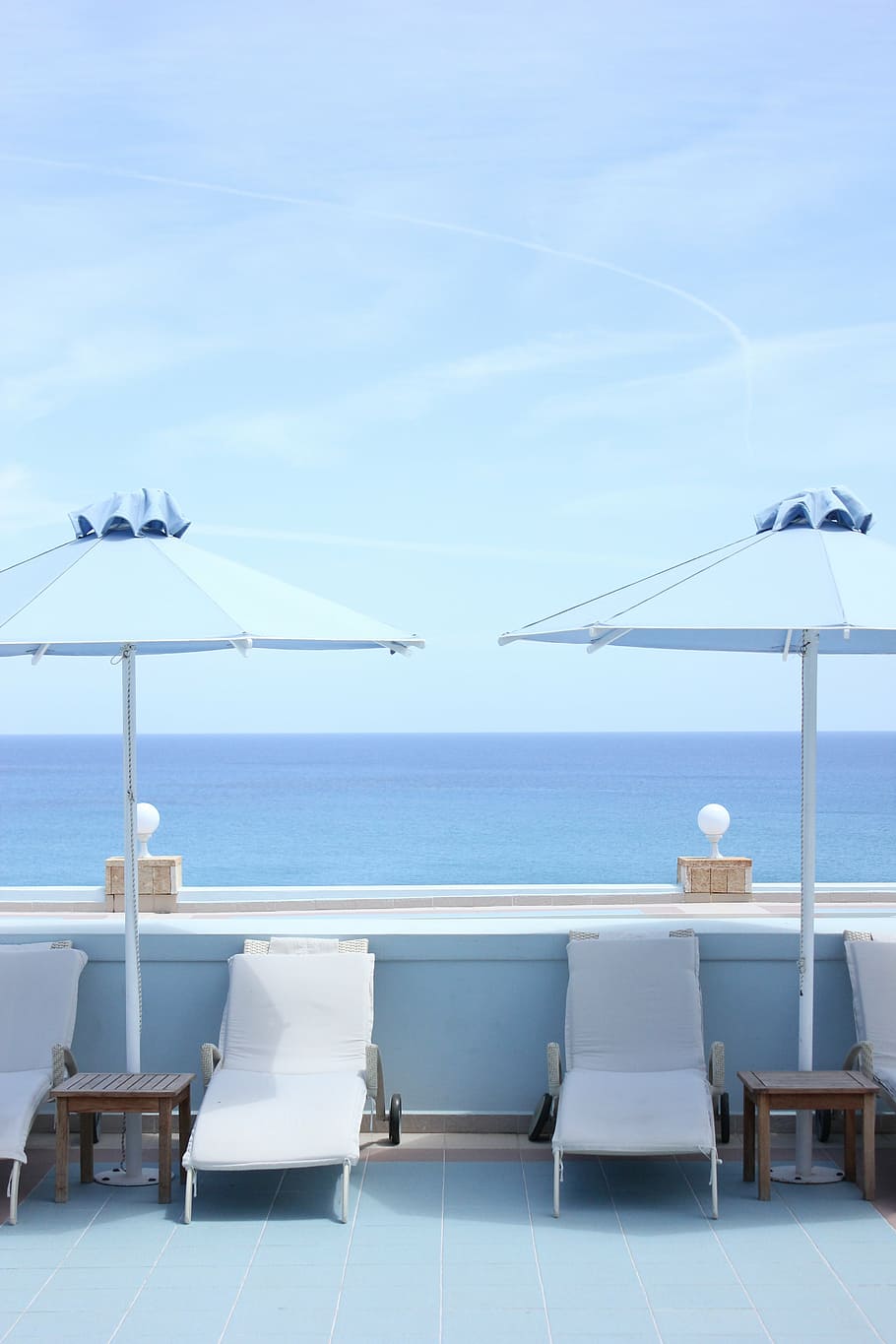 four, white, outdoor, loungers, shade, two, blue, parasols, overlooking, sea