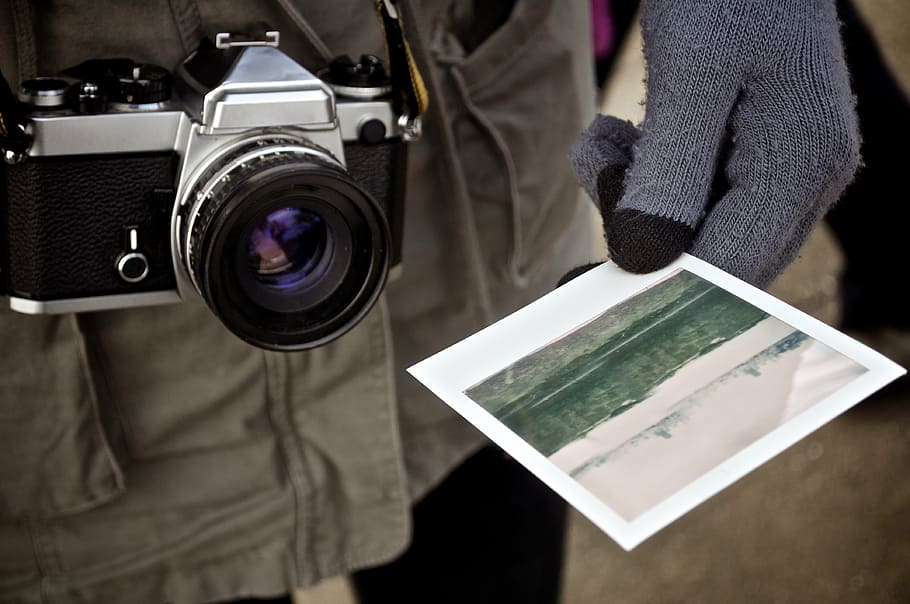 person, holding, landscape photo, gray, black, bridge, camera, paper, print, polaroid
