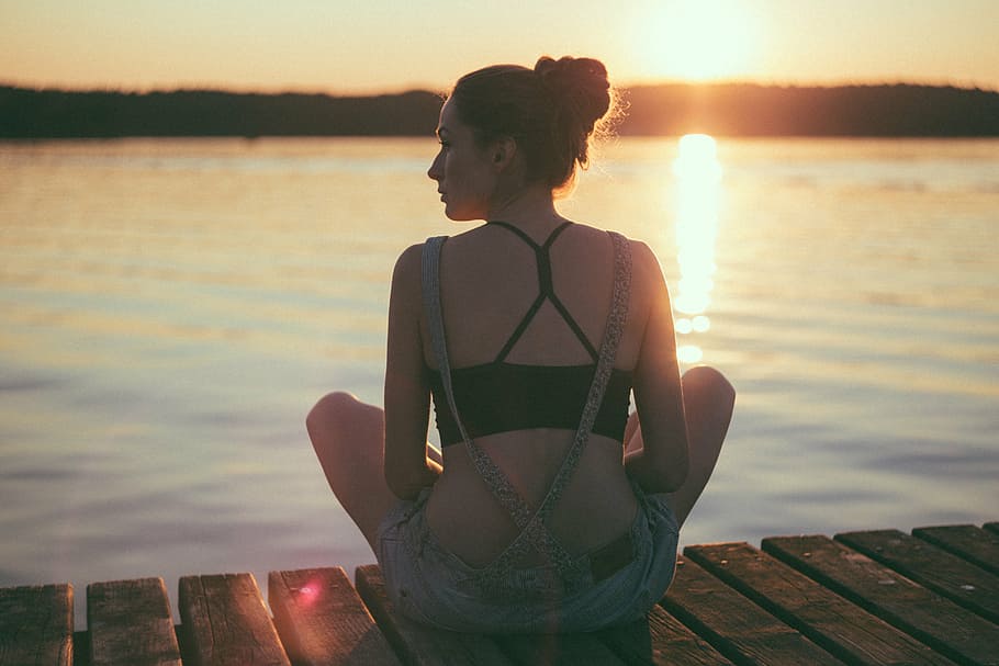 woman, sitting, brown, wooden, docking boat, black, strappy, back, crop, top