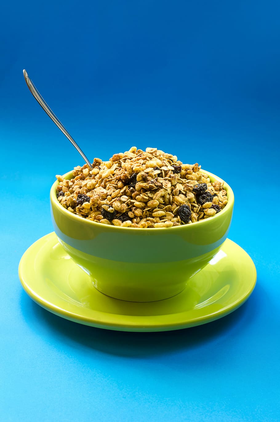 green, bowl, filled, cereal, food, plate, spoon, raisins, peanut, blue background