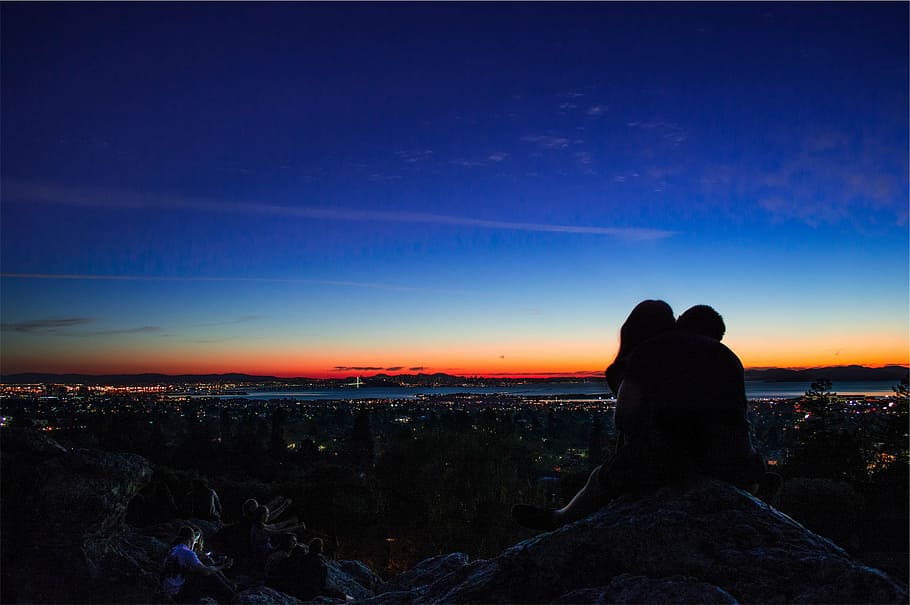 foto de silueta, pareja, sentado, roca, silueta, dos, personas, mirando, puesta de sol, anochecer