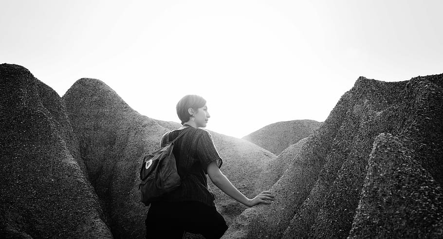 woman, holding, rock, daytime, black, white, rocks, hill, cliff, black and white