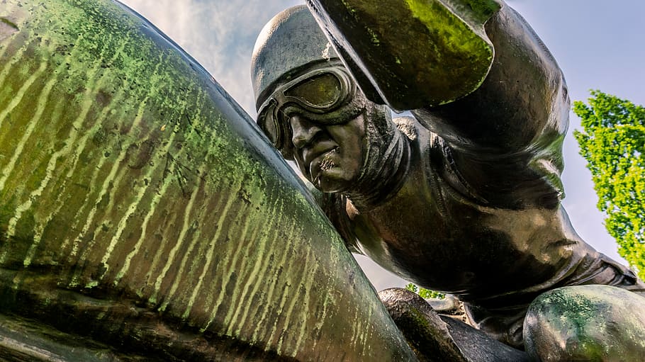 man, wearing, half-face helmet, aviator goggles statue, monument, figure, sculpture, race car driver, motorcycle, statue