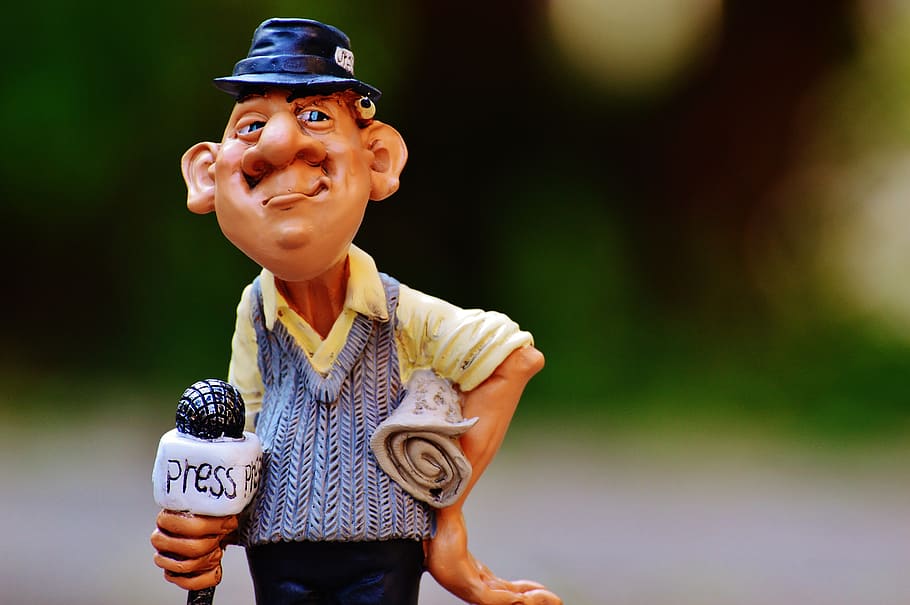 shallow, focus photography, brown-haired man, holding, white, microphone bobblehead display figure, journalist, press, newspaper, journalism