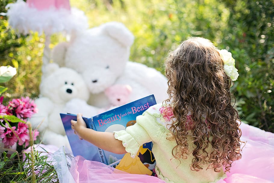 toddler girl seats, front, white, teddy, bears, holding, book, little girl reading, garden, child