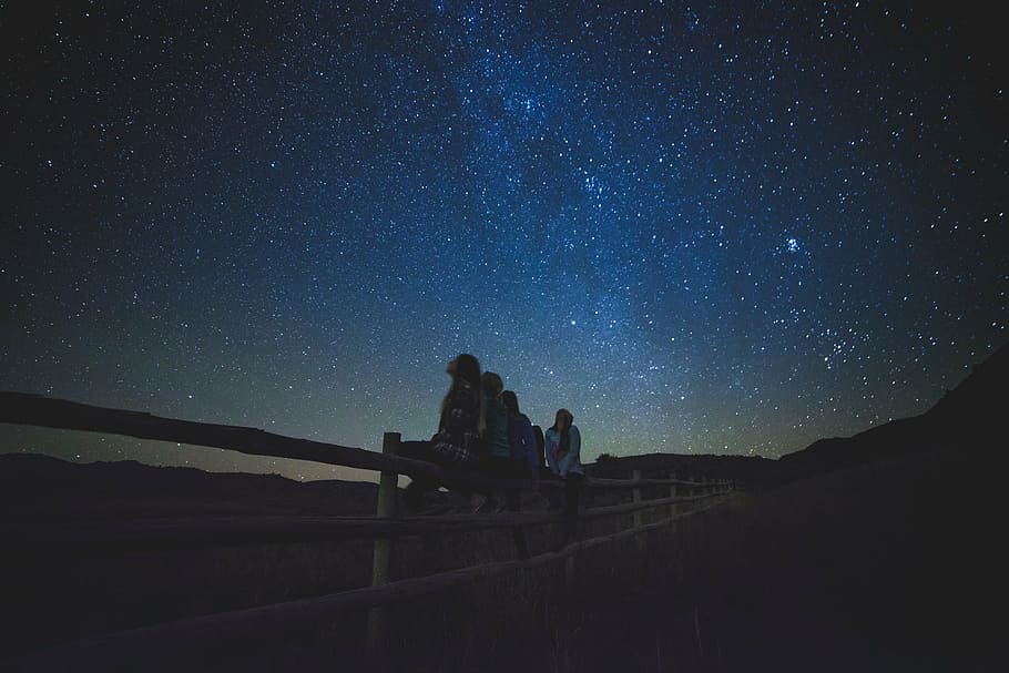 people, sitting, fence, looking, nighttime, five, person, watching, galaxy, stars