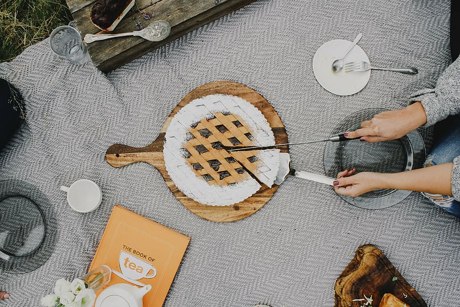 person, putting, pie, brown, wooden, pie server, outdoor, camping, plate, utensils