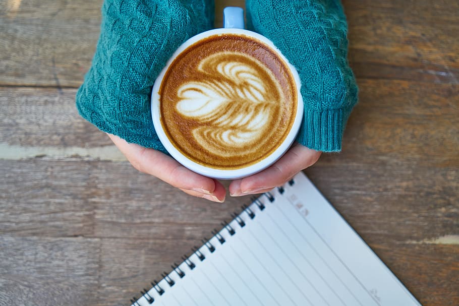 person, holding, heart cappuccino, hands, white, springside, lined, notebook, wooden, surface