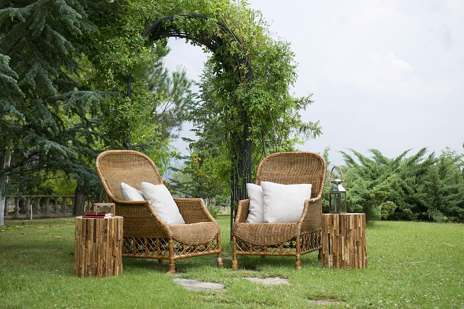 two, brown, wicker armchairs, white, throw, pillows, round tables, grass field, patio, armchairs