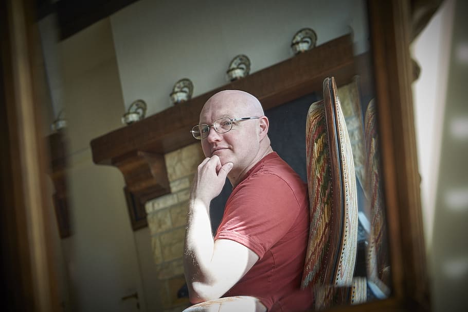 man, sitting, chair, fireplace panel, bald, family home, antique interior, thinking, eyeglasses, one person