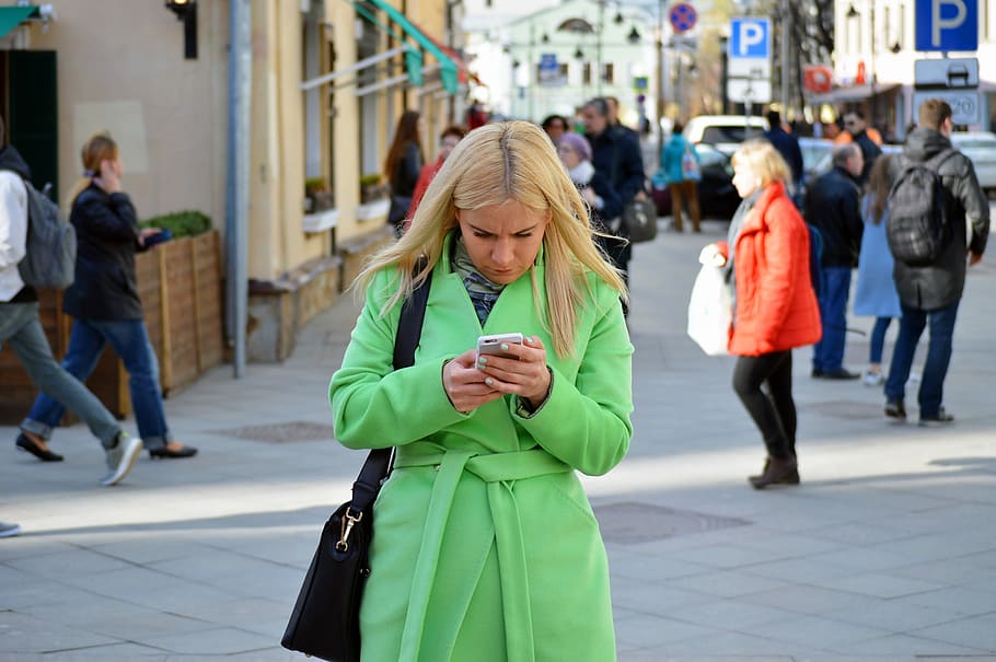 woman, green, coat, holding, phone, behind, people, woman in green, pretty, girl