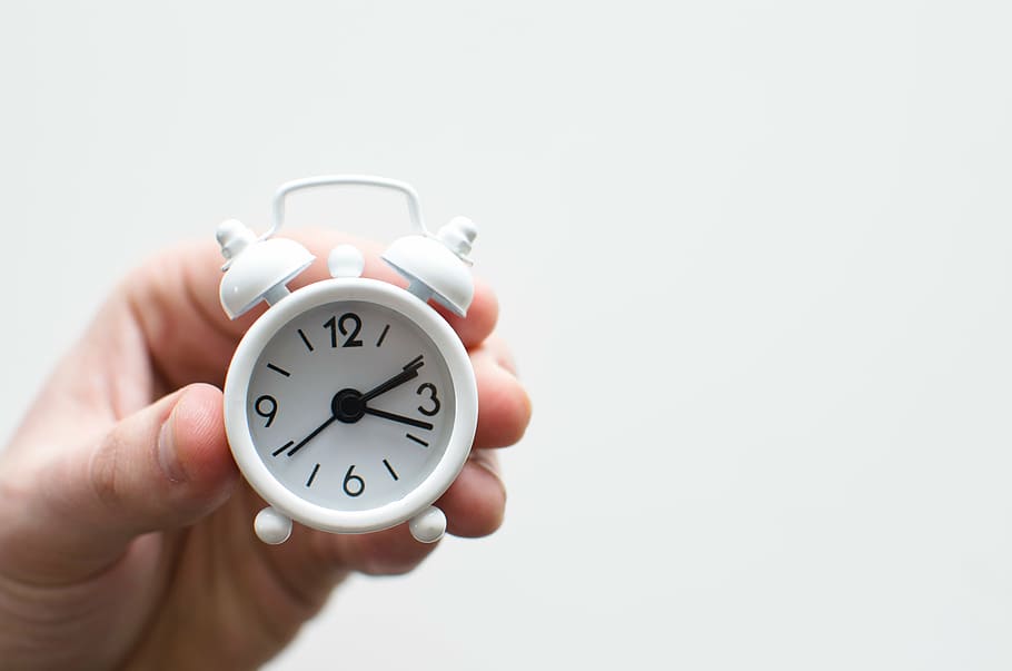 person, holding, white, analog desk clock, tiny, alarm, clock, time, hand, alarm Clock