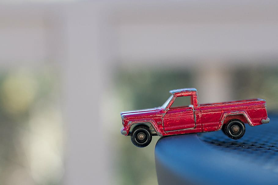 toy car, edge, playing, driving, focus on foreground, red, day, close-up, selective focus, single object