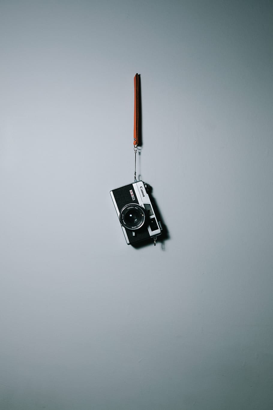 black, grey, slr camera, hanging, wall, camera, white, surface, canon, lens