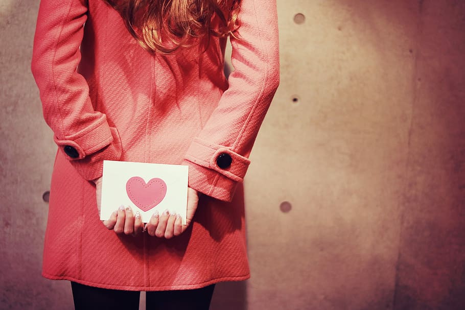 woman, wearing, pink, coat, holding, back, love letter card, holding back, love letter, letter card