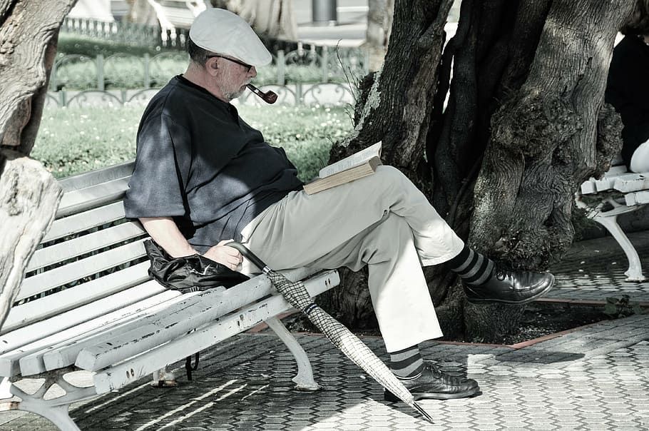 man, black, shirt, sitting, bench reading book, reading, park, pipe, umbrella, peaceful