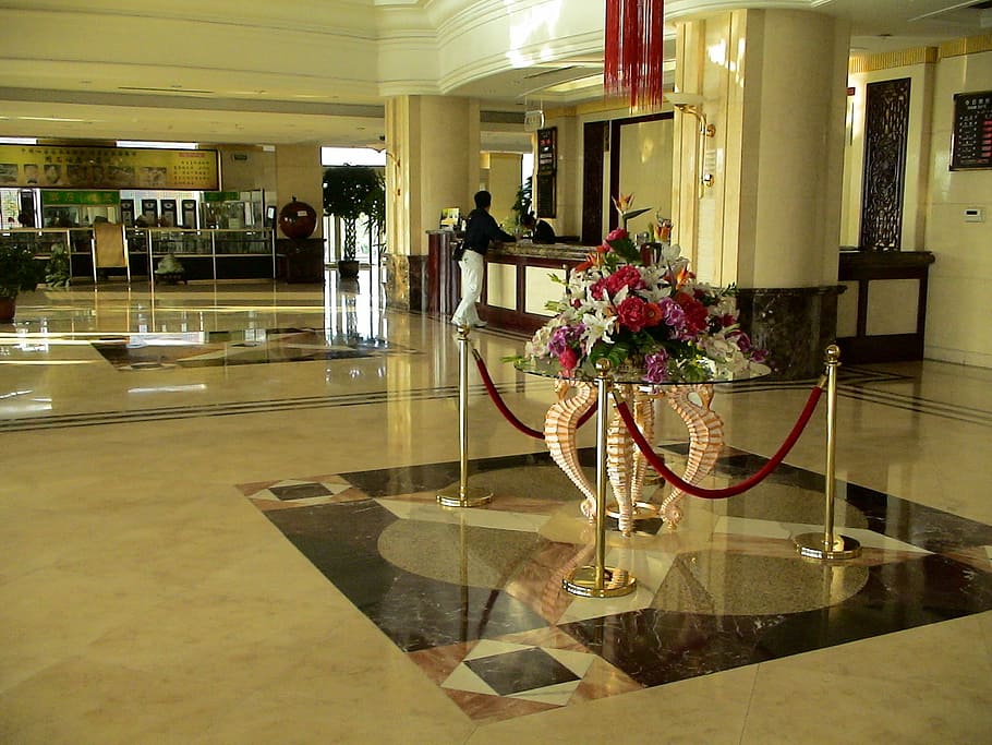 assorted, flowers bouquet centerpiece, clear, glass coffee table, stanchions, person, counter desk, reception, hotel, entrance hall
