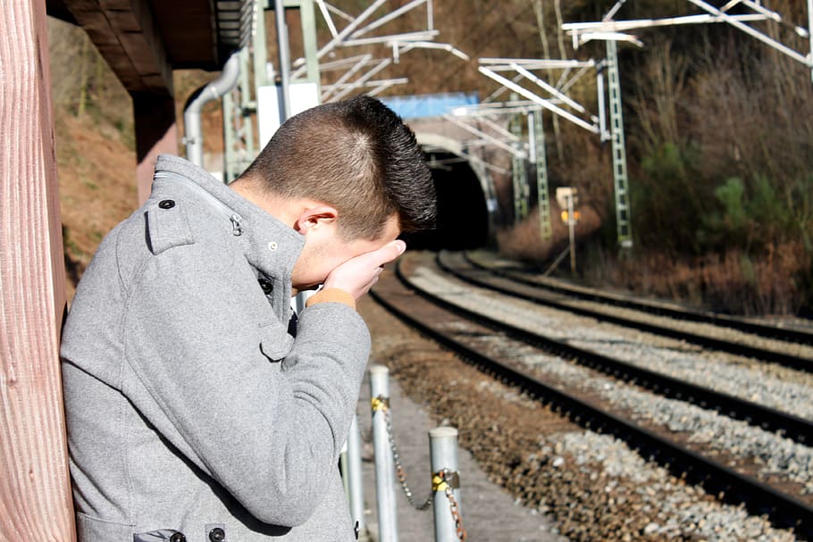 man, leaning, brown, wall, holding, face, young people, melancholy, sad, railway station