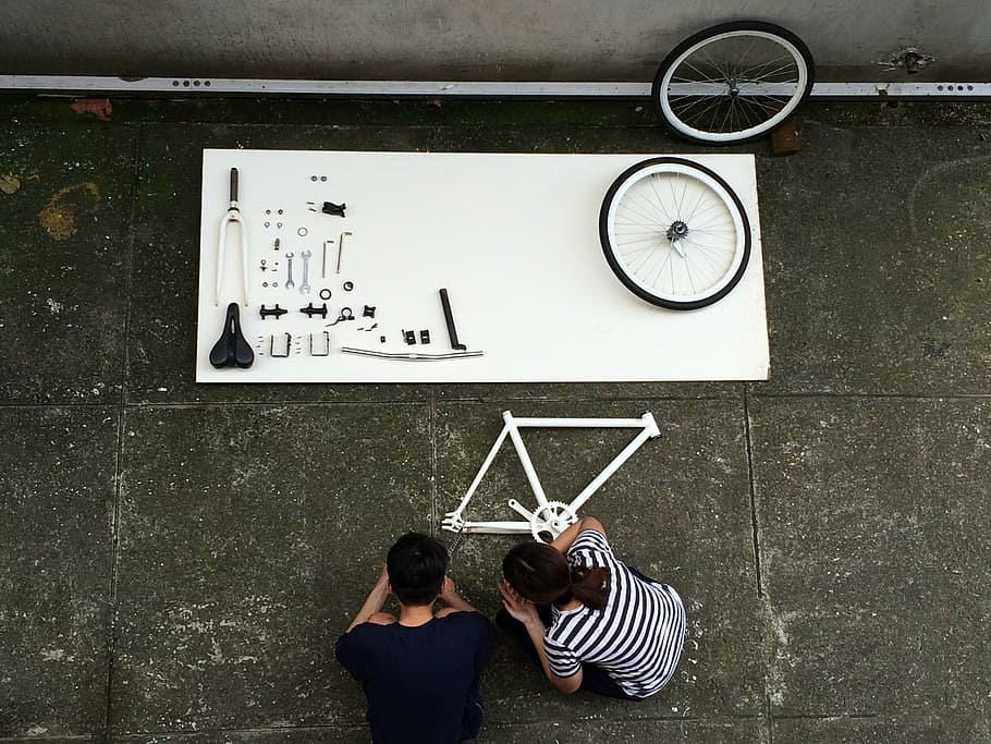 homem, mulher, agachado, peças de bicicleta, montagem de uma bicicleta, componente, bicicleta, vista superior, preto e branco, construtor