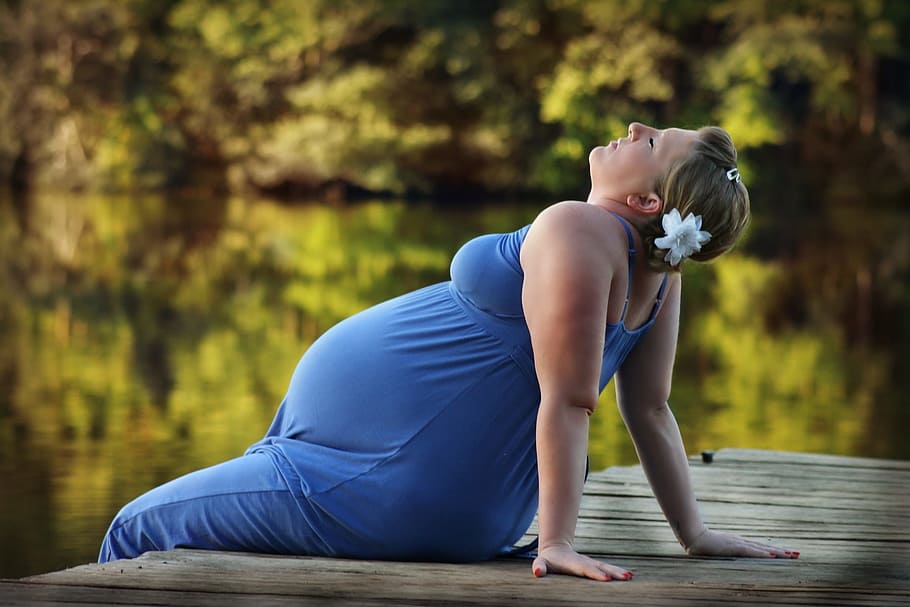 selective, focus photography woman, blue, dress, sitting, deck, woman, pregnant, pier, belly