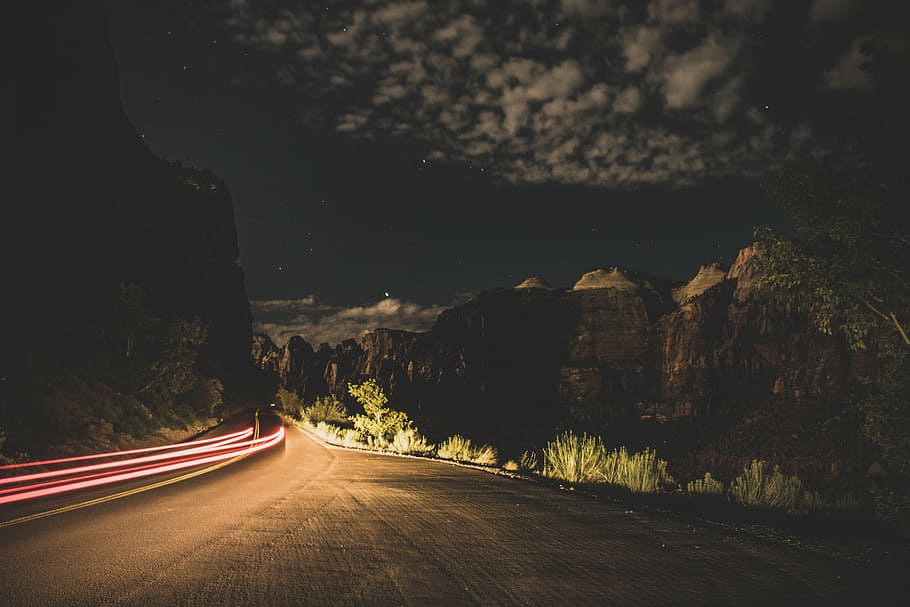 fotografía de lapso de tiempo, carretera, rodeado, colinas, negro, asfalto, noche, oscuro, luces, hierba