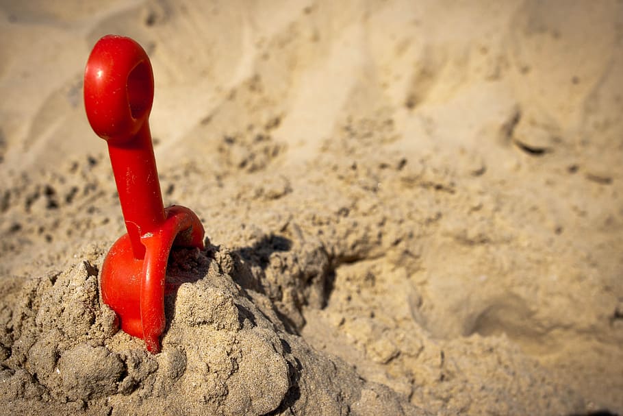 red, plastic scoop, brown, sand, beach, sunlight, shovel, toy, summer, seaside