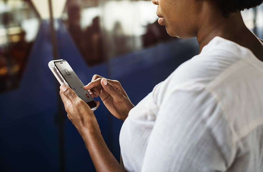 mujer, de pie, sosteniendo, teléfono inteligente Android, africano, teléfono celular, chat, comunicación, conexión, datos