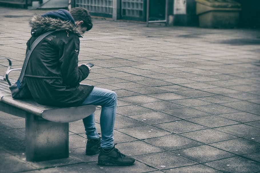 man, black, jacket, denim jeans, sitting, gang chair, holding, smartphone, people, alone