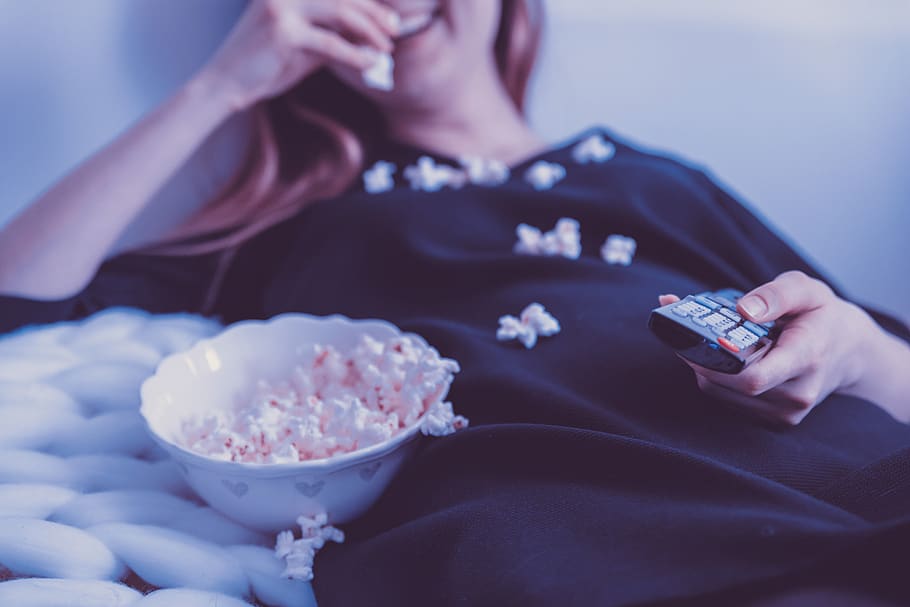 woman, eating, popcorn, blond, smile, happy, television, tv, remote control, remote