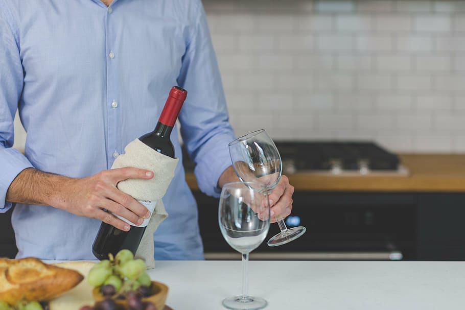 man, holding, round, clear, glass footed wine cup, inside, kitchen room, people, wine, serve