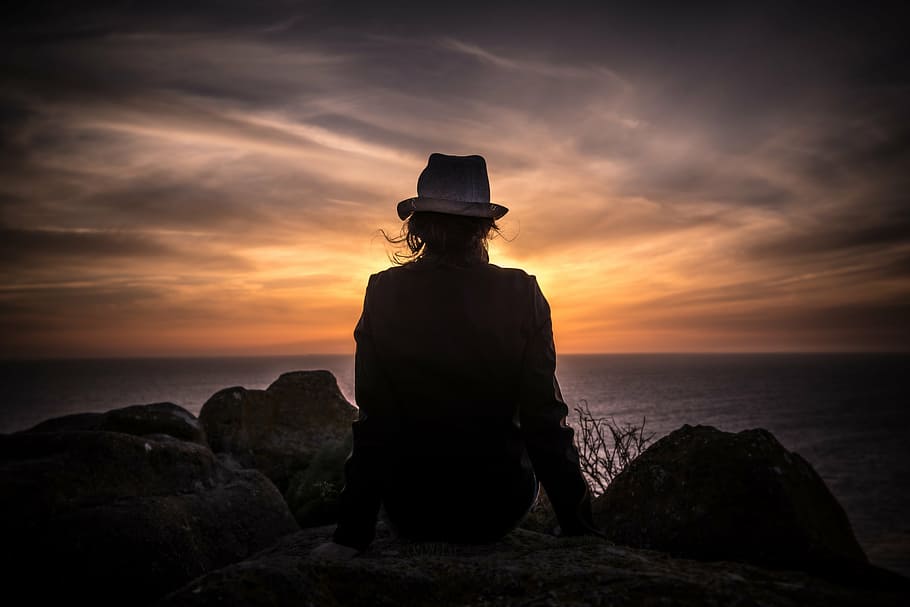 silhouette photograph, person, sitting, mountain cliff, silhouette, wearing, hat, woman, girl, lady
