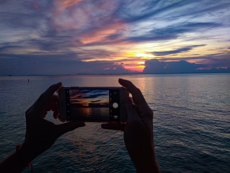 sunset in the phone, holding phone, smartphone, mobile phone, thailand, island, sunset silhouette, holding phone at sunset, woman taking pics of sunset, taking s of sunset