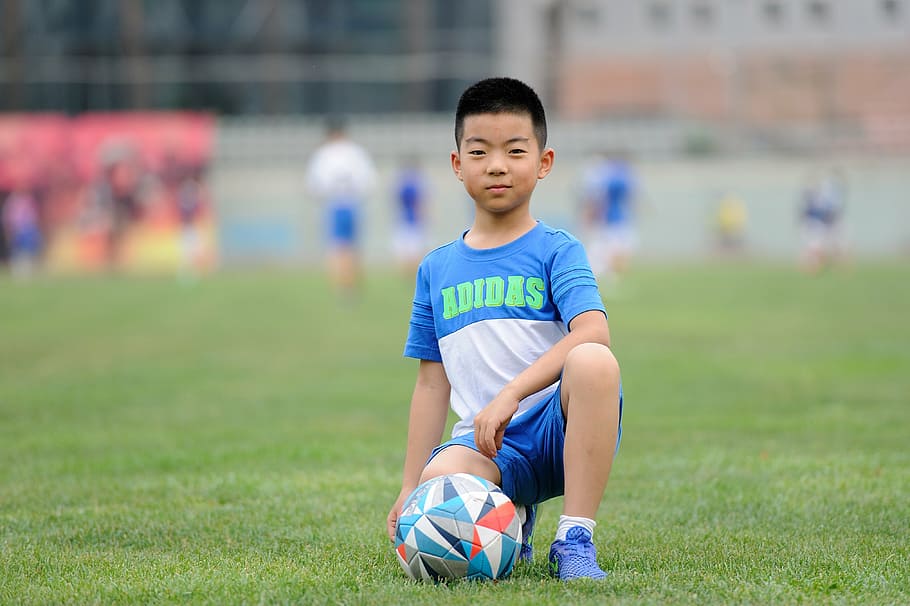 boy, kneeling, ground, soccer ball, football, teenager, greenery, sports, kids, train