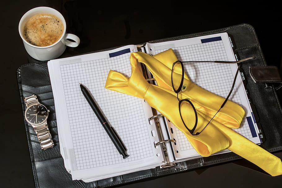 eyeglasses, white, graphing notebook, agenda, tie, pen, men's watch, cup of coffee, reading glasses, appointment calendar