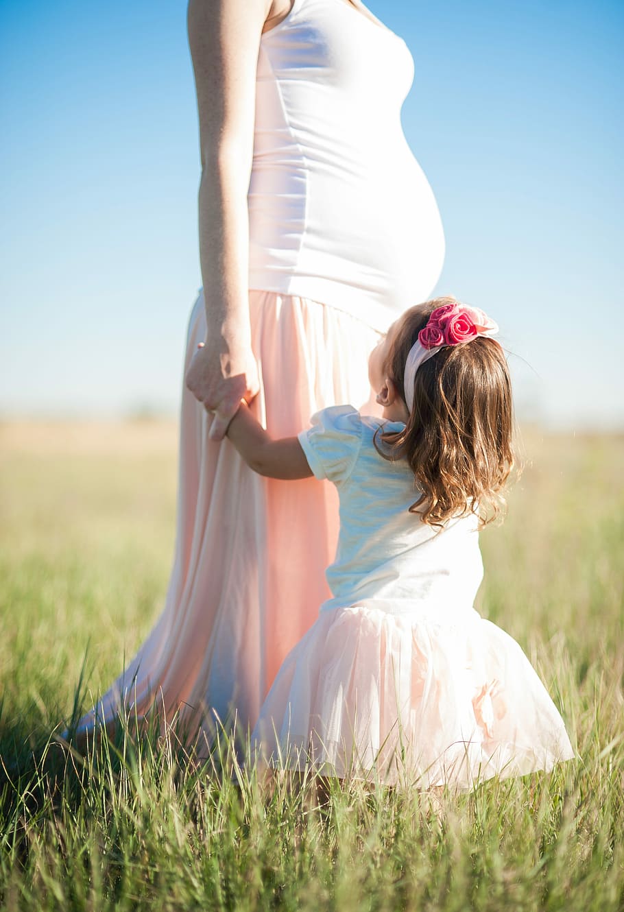 girl, white, pink, puff sleeve dress, pregnant, mother, standing, green, grass, daytime