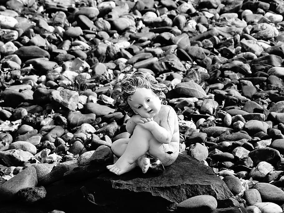 greyscale photography of child, solid, rock, representation, toy, human representation, day, nature, abundance, high angle view