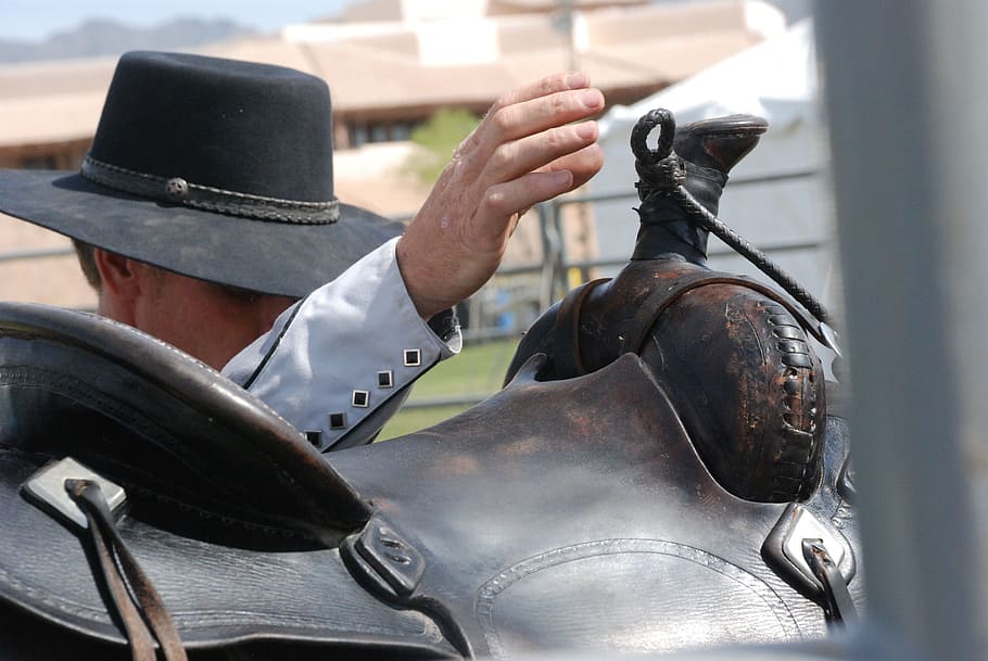 person, hold, black, leather horse saddle, cowboy, close up, western, cowboy hat, hand, saddle
