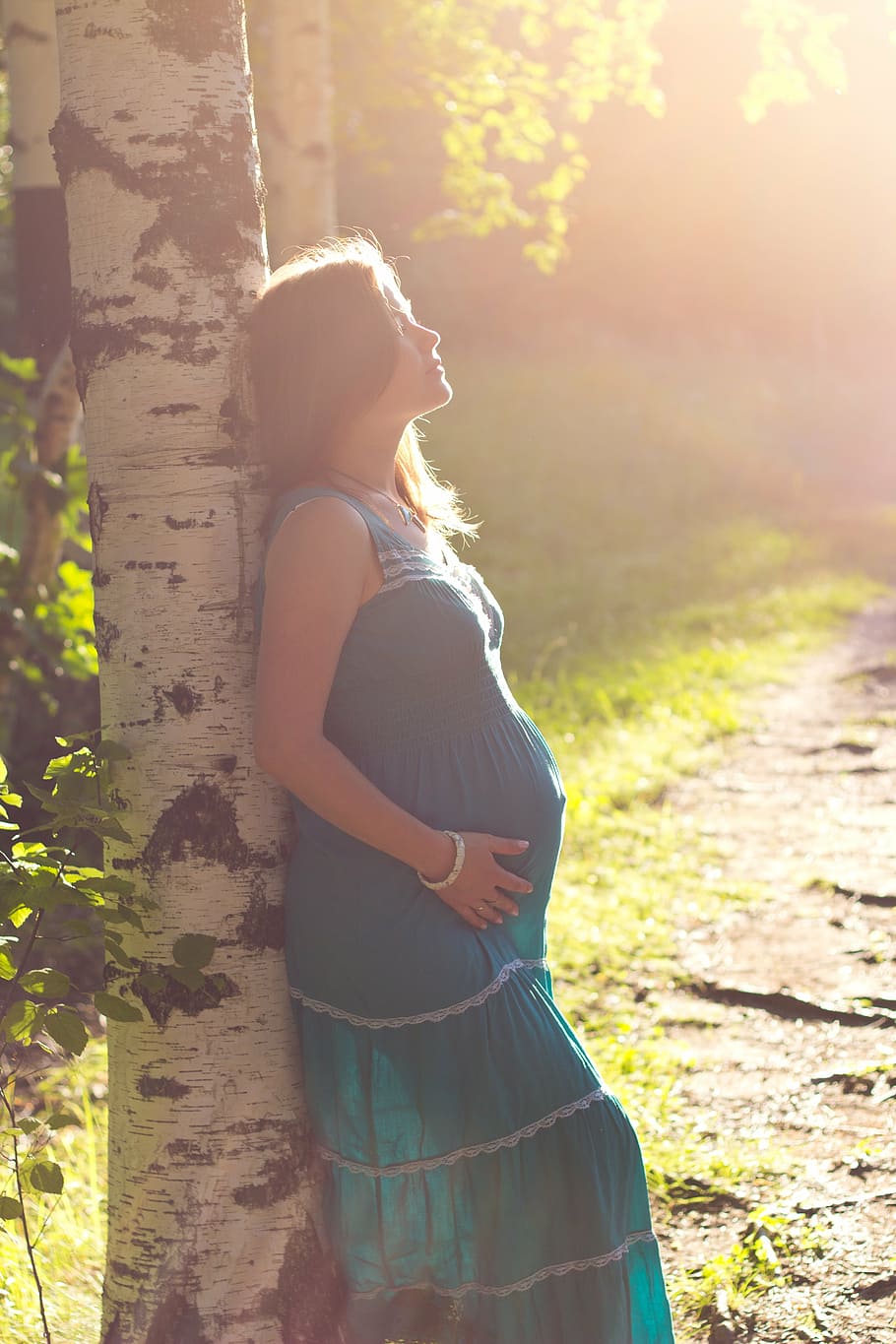 hamil, wanita, mengenakan, biru, gaun maxi, bersandar, pohon, kehamilan, kegembiraan, de