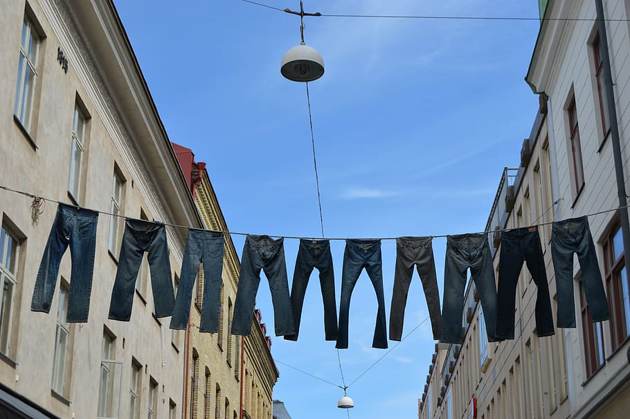 assorted-sizes denim jeans, hanged, clothes line, across, two, buildings, daytime, pants, gothenburg, two thousand and thirteen