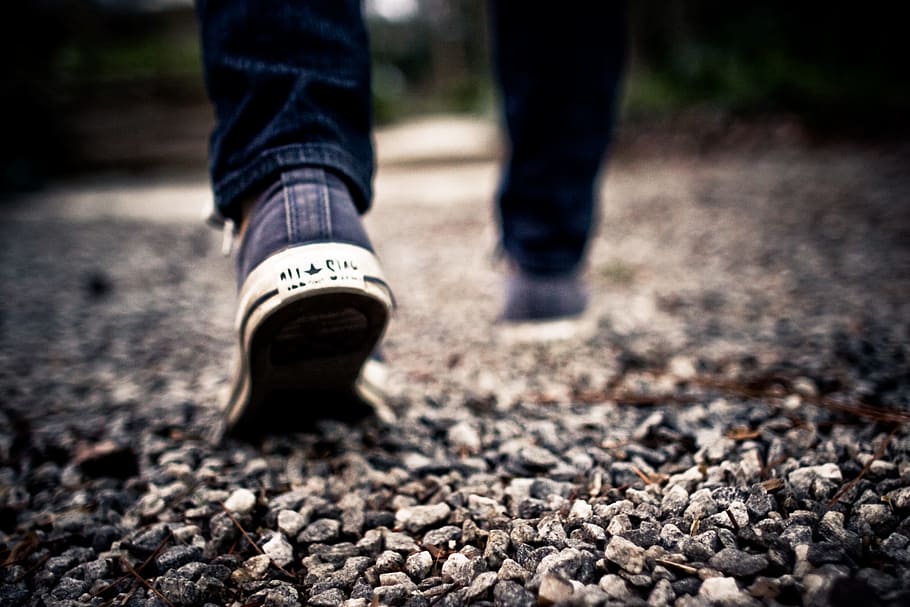 man, wearing, blue-and-white, low-top sneakers, walking, rock road, white, Converse, low, top