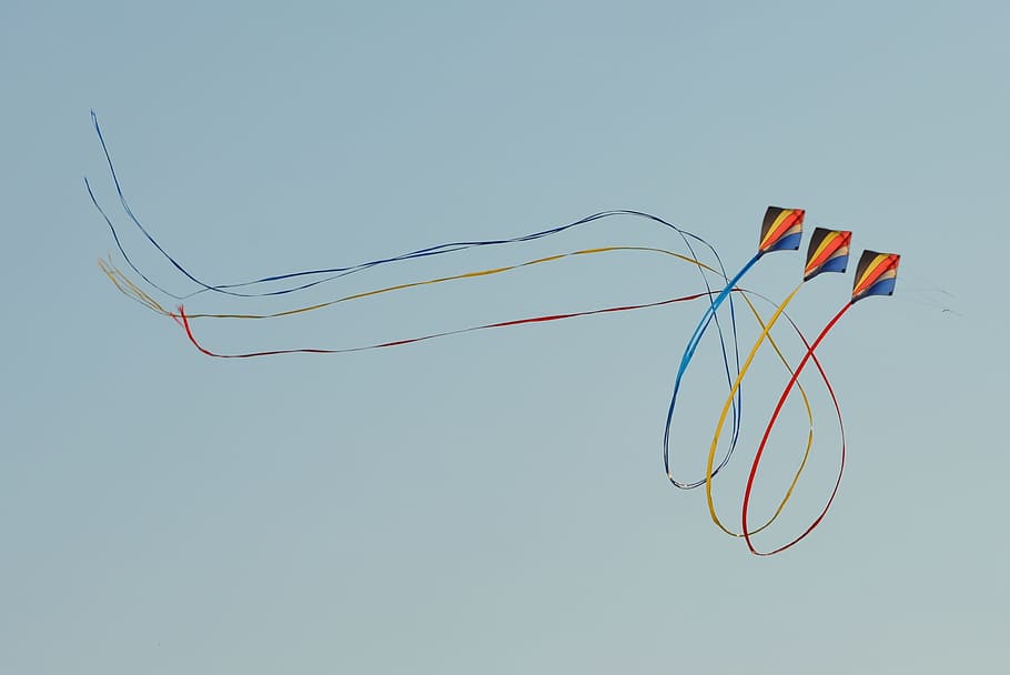 three black-yellow-and-orange kites, bottom, view, flying kites, wind kite, blue sky, air, looping, ribbons, dom