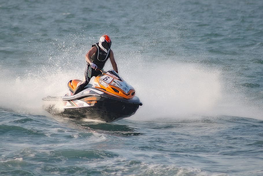 man, riding, orange, black, jetski, wearing, full-face helmet, jet ski, navigation, driver