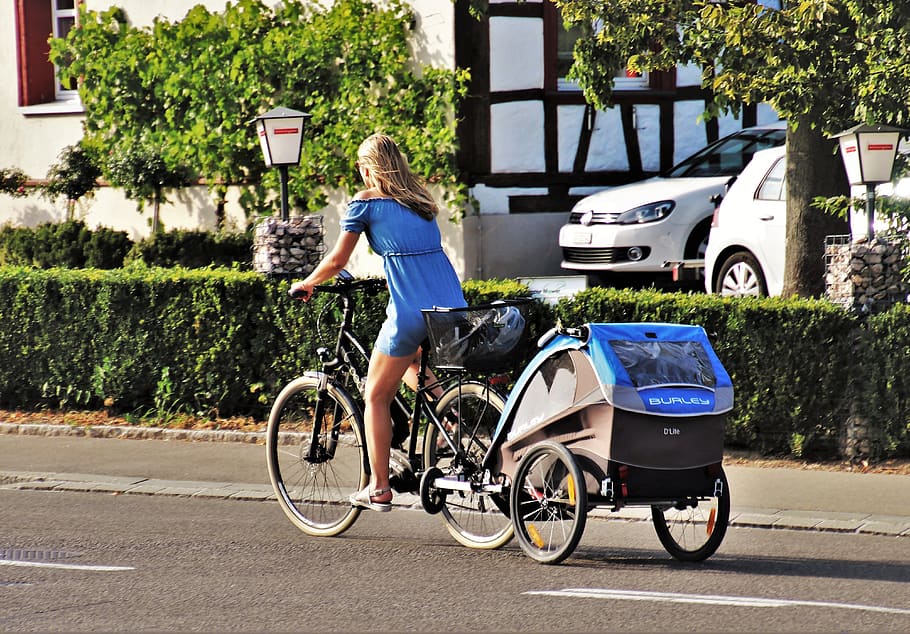 A lady riding a bike with a trailler
